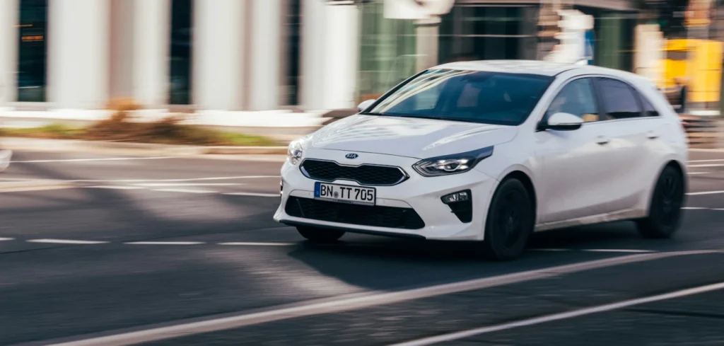 A white car driving on a quiet road.
