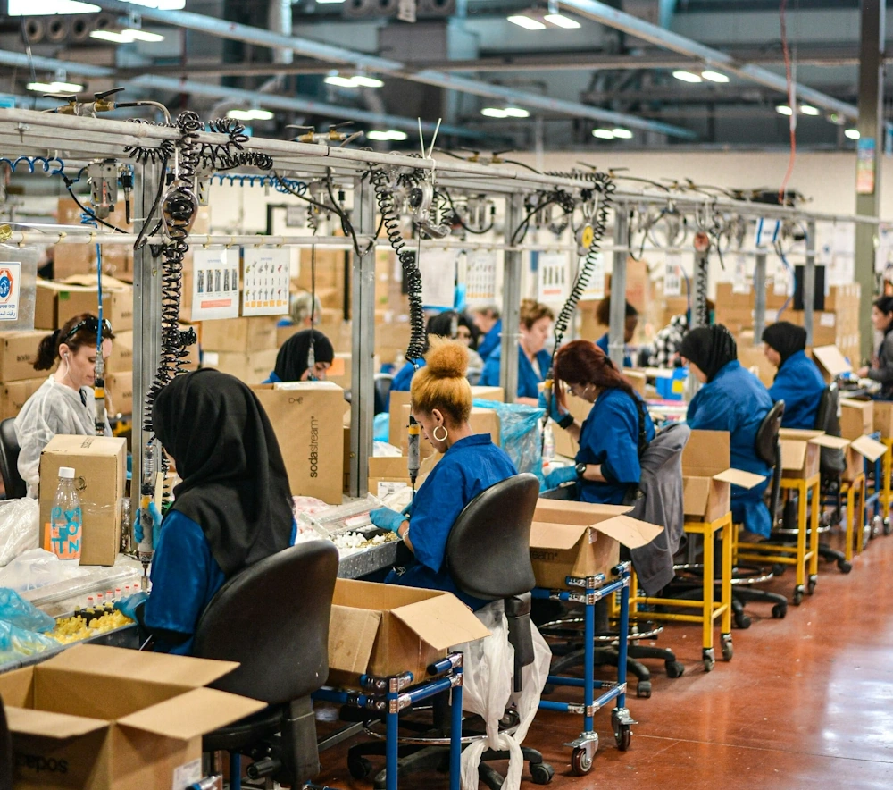 A row of workers at stations in a busy factory