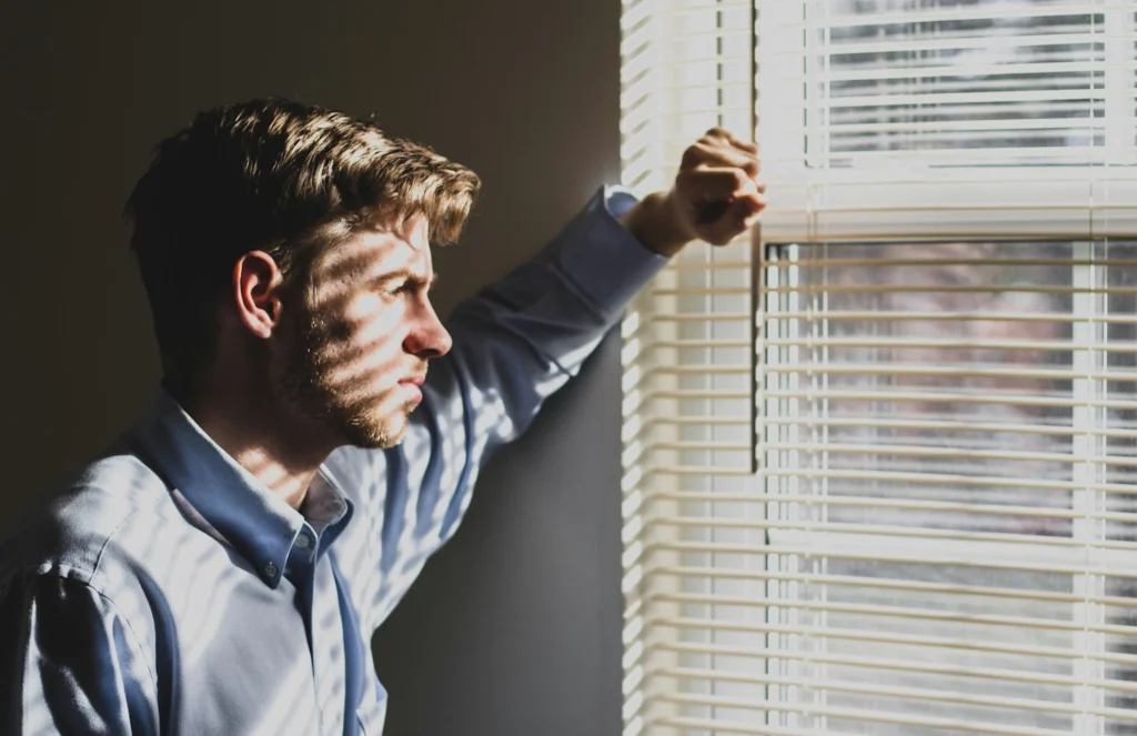 A man looking thoughtfully through a window.